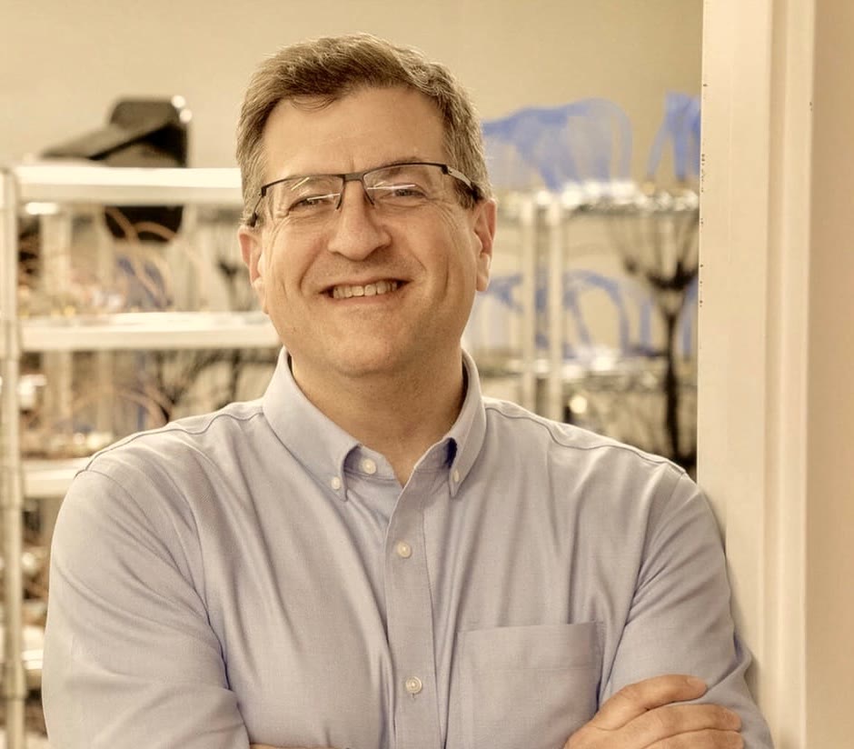 Steve Chazin, who made Tellie, smiling with his arms crossed in front of a rack of Macs.